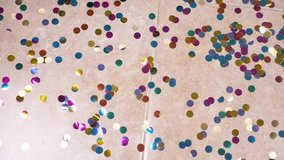 slow motion. 4k. round multicolored confetti lie on the tiled floor. dolly shooting