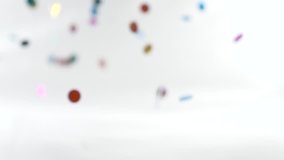 super slow-motion shooting. round multicolored confetti fall and whirl in the air.