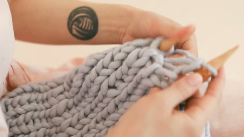 Knitting close up. Womans hipsters hands with cool tattoo .Video footage