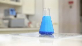 Cinemagraph of blue liquid boiling in glass conical flask standing on table in lab - Powered by Shutterstock - Get 15% off with code: PIKWIZARD15