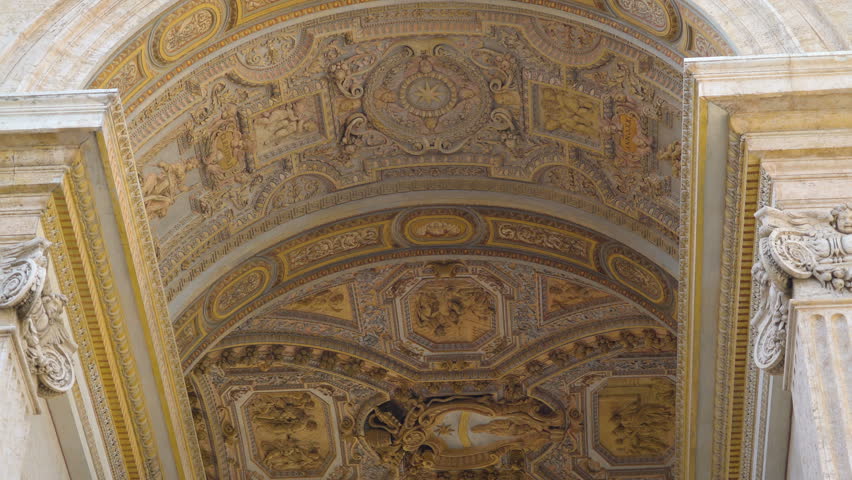The art sculpture on the ceiling of Basilica of Saint Peter in Rome Italy with the white wall of the church