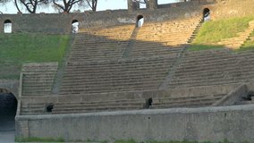 The stairs on the walls of the ampitheatre in Pompeii Italy with the sun shining on the park