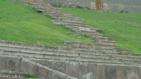 Closer look of the stairways in the ampitheatre in Pompeii Italy and the green grasses on the side of the stairs