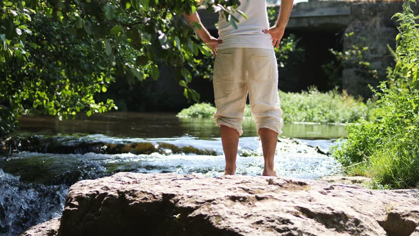 Man on a rock contemplating the river