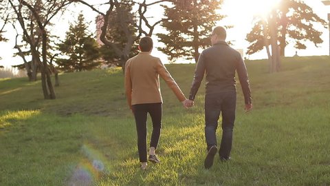 Gay couple walking together holding hands. The concept of same-sex relationships