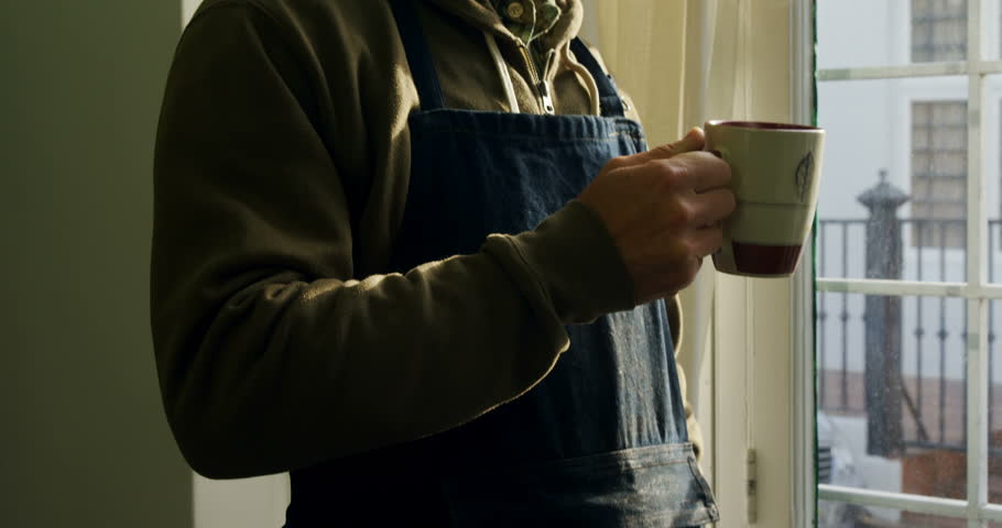 Craftsman having coffee while looking through window in workshop 4k