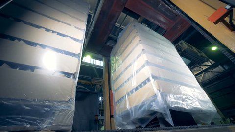 Factory equipment packages boxes with bottles, sealing them at a plant. 4K.