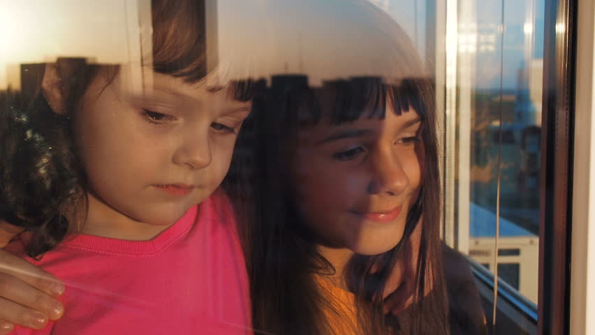 Children at the window. Little girls look out the window.
