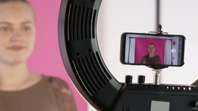 Teen girl vlogger recording video blog for her lifestyle channel in home vlog studio. Girl pushing start stop record button on phone screen and talking to camera. Blogger using smartphone for vlogging