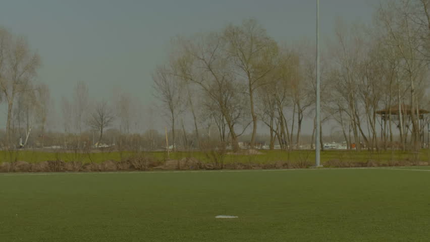 Young footballer kicking soccer ball on football pitch during training session. Soccer player hitting ball with foot while exercising shots on goal on sports field.