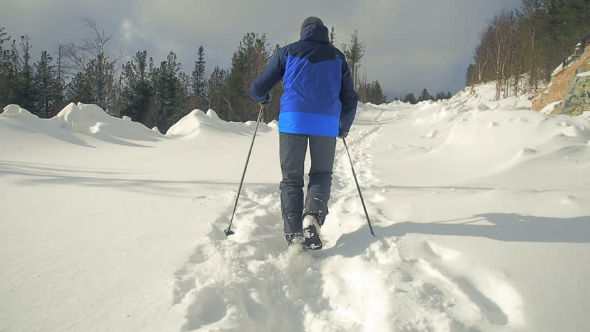 Hiker man hiking in winter.  Snow mountains. Slow motion: young active hiker man trekking,  snow trail. 
