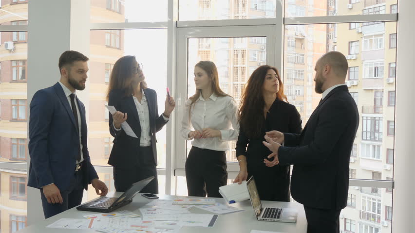 Office workers, employees of a large company, two young men and three young women standing near a table with documents, two men argue about the inconsistencies of a new contract with another firm Royalty-Free Stock Footage #1010082566