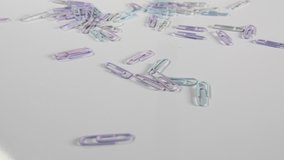 4K of pastel paper clips in a pile on a white surface, office and work coloured stationary in close up dolly shot.