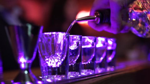 Shots of alcohol being poured on bar