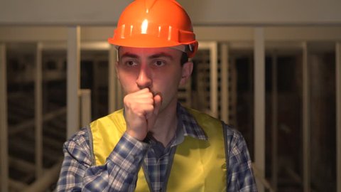 Sick worker or an engineer or architect coughing on construction site, Cough. Concept: construction, worker, engineering, design, health