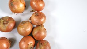 4K Mans hand picks up and checks fresh brown onion from pile vegetable on white background 