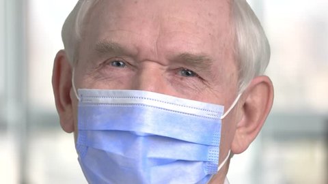 Portrait of senior surgery doctor. Close up face of old male doctor with blue mask.