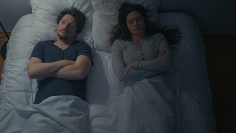 Above view of couple in bed distant and quiet after argument.