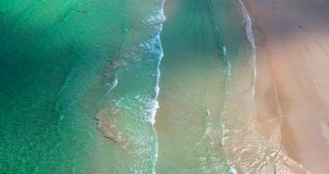 AERIAL 4K: Tropical beach video loop showing seamless never ending footage with aerial bird eye view of green foaming ocean waves crushing against the sandy coast line