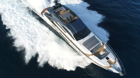 Aerial perpendicular view of a luxury yacht navigating fast.