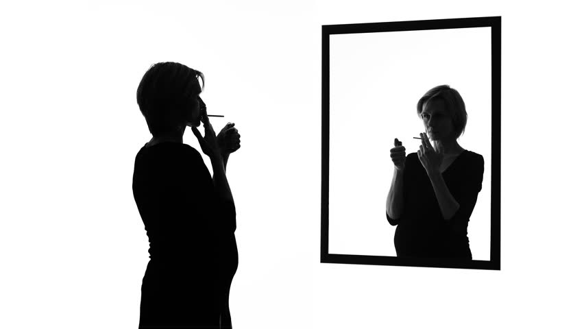 Conscience-stricken pregnant woman smoking cigarette in front of mirror, habits