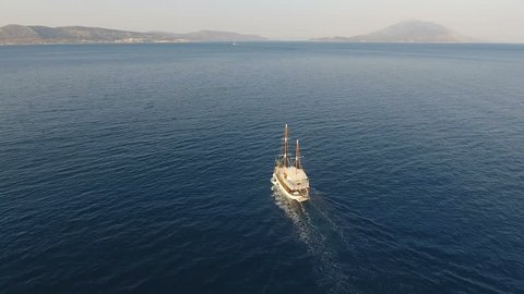 A yacht with traditional design is traveling slowly in the calm sea