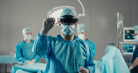 Front view half portrait of surgeon using augmented reality holographic hololens headset, preparing for operation in modern operation theater. 4K UHD 60 FPS SLO MO