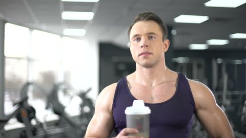 Muscular man drinking protein shake after workout, healthy diet, bodybuilding