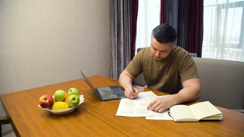 online education. e-learning. computer internet technology. adult caucasian man writing, working on laptop, studying at home