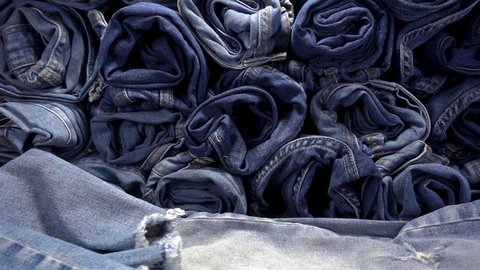 Slow Motion of falling jeans on a pile of denim  trousers.