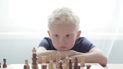 A boy plays with his father in chess. Dad teaches him new moves