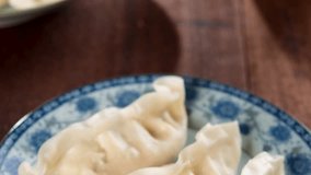 Fresh dumpling on plate. Chinese cuisine with hot steams on rustic vintage wooden background. Fractal on the plate is generic print. 4k footage video.