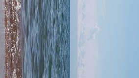 Vertical video. Surf on Lake Issyk-Kul in the background of mountains, beach town of Cholpon Ata, Kyrgyzstan