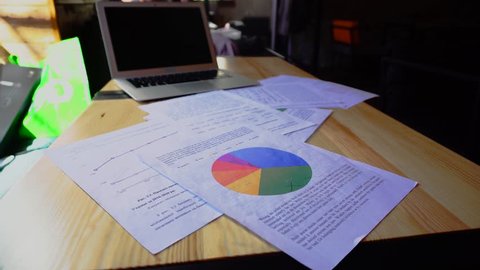 Close up documents with color diagram and laptop on table. Concept of home workplace.
