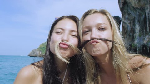 Best friends hang out on long tail boat at Phi Phi Islands, best friends portrait of them using their hair a moustache. Slow motion.