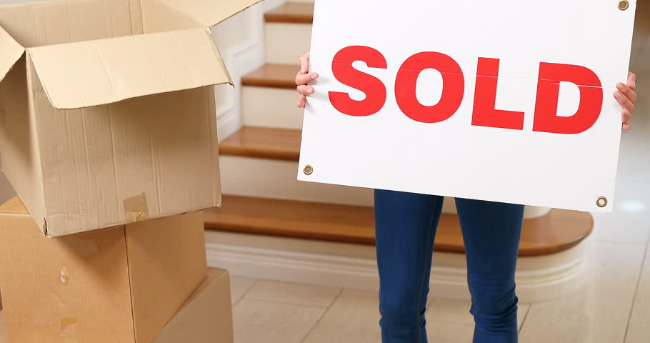 Smiling young woman holding sign board in her hands at home 4K