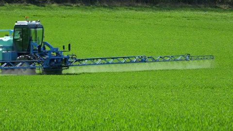 Agriculture fertilizer working on farming field, agriculture machinery working on cultivated field and spraying pesticide, France