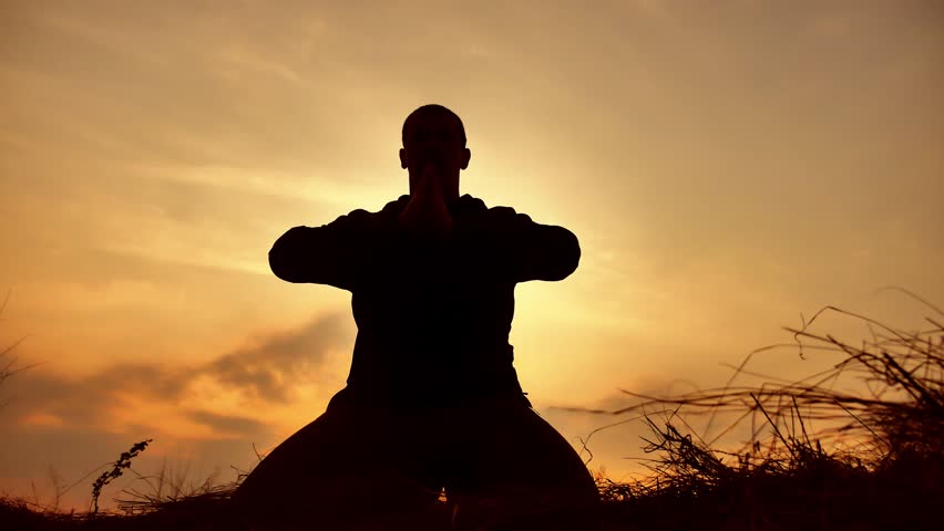 silhouette of a male monk engaged in meditation at sunset sunlight. Buddhist prays at sunset healthy way of lifestyle life nature Royalty-Free Stock Footage #1010155259