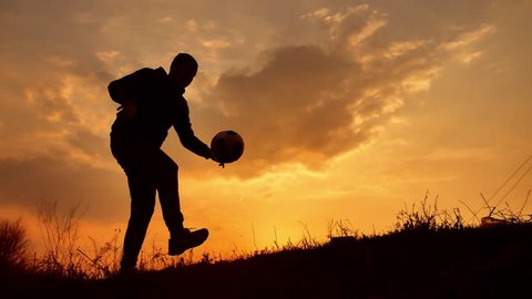 man coins a ball European the football soccer freestyle silhouette at sunset sunlight. man beats chasing ball football outdoors world championship lifestyle