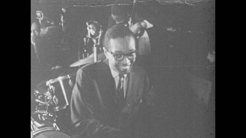 1960s: Jazz trio plays instruments on small stage. The Billy Taylor Trio plays for audience. Audience applauds.