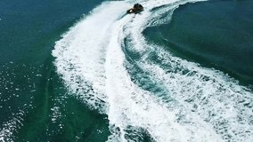 Aerial video from jet ski making extreme manoeuvres while cruising in high speed over deep blue open ocean sea