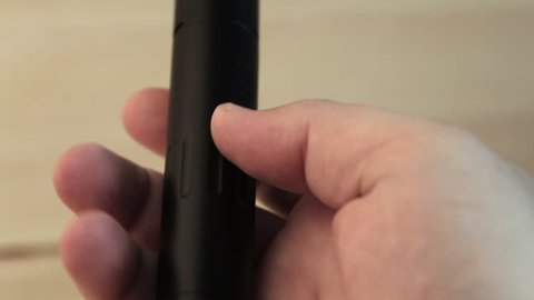 Vape pen or vaping device in man hand close up, macro. Mech mod with RDA atomizer, selective focus
