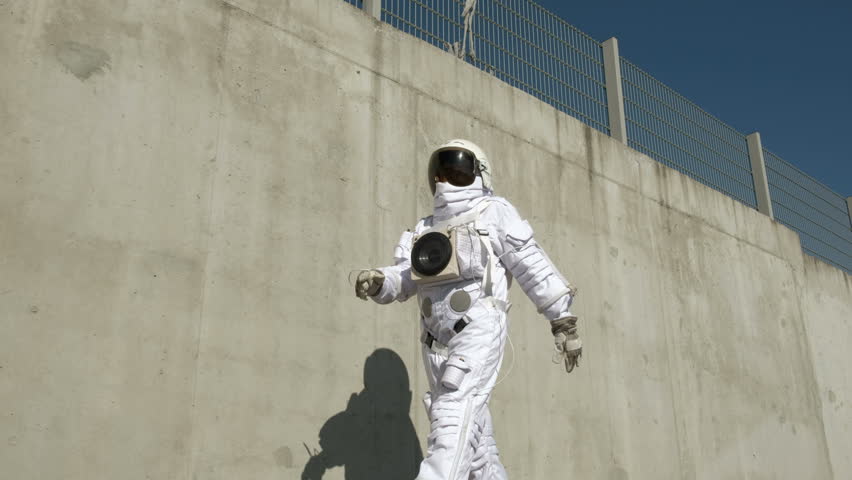 The cosmonaut walks around the city. An unusual scene from the city.