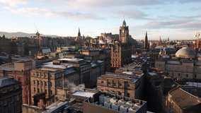 4K aerial drone video of a clock tower, castle, and ancient buildings in Edinburgh, Scotland during the morning