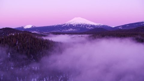 Mt. Bachelor, Oregon circa-2018.  Early morning aerial view of Mt. Bachelor with low fog over trees. Shot from helicopter with Cineflex gimbal and RED Epic-W camera. 