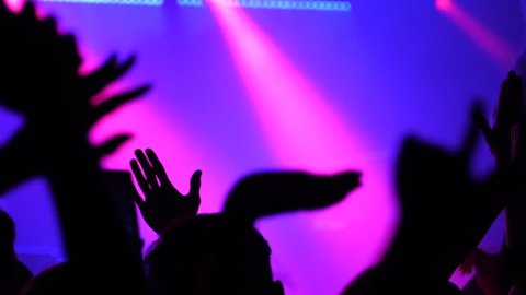 Dancing people silhouettes slow motion in disco concert stage lights raise hands enjoying rhythm