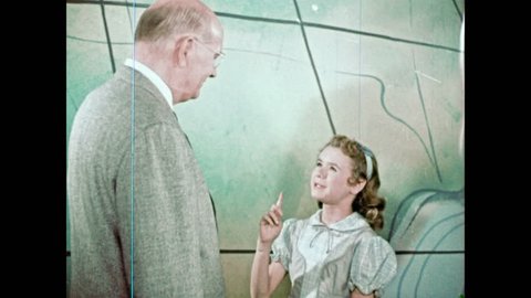 1950s: Little girl and man in suit smile and talk. Jabberwocky, Mad Hatter, little girl and man turn and look at the oversize globe.