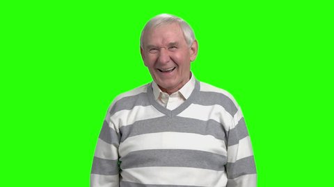 Old man laughing in green studio, slow-motion. Friendly grandfather laughing against green hromakey background.