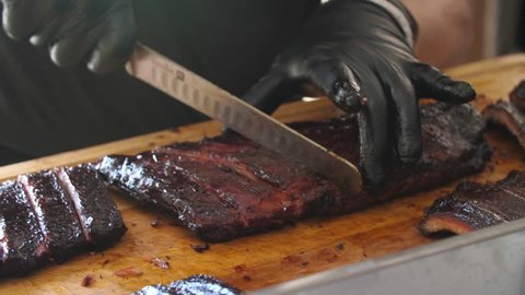 Close-up of a professional cutting BBQ ribs for serving.