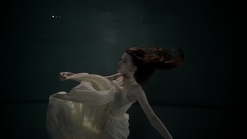 a young marine nymph moves her hands under the water, with movements and dives flutters a lush wedding dress, a woman emerges upstairs for a breath of air